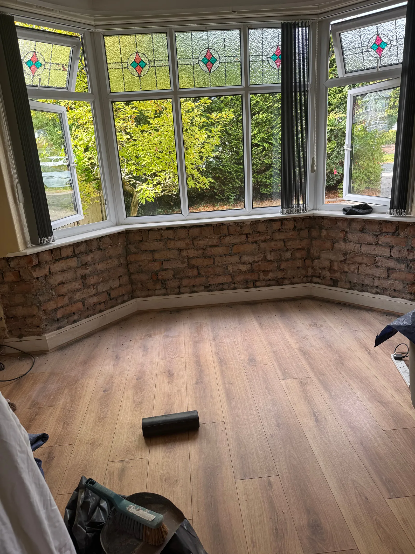 The bay window wall before work, plaster blown and stained at skirting level.