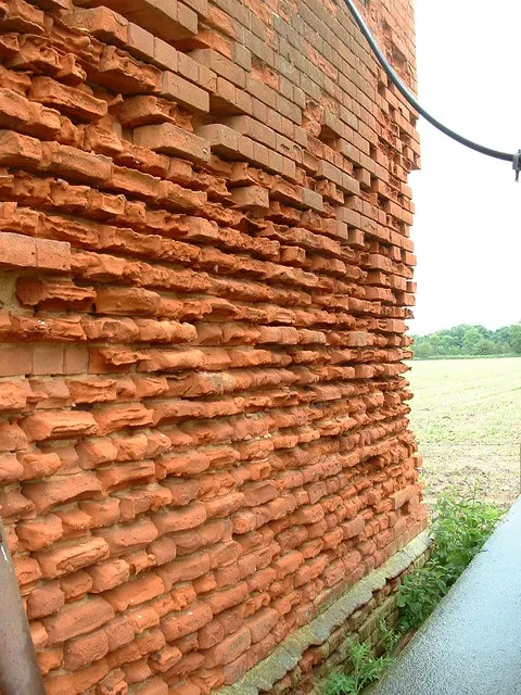 Old brickwork with its faces and mortar joints worn away by the weather