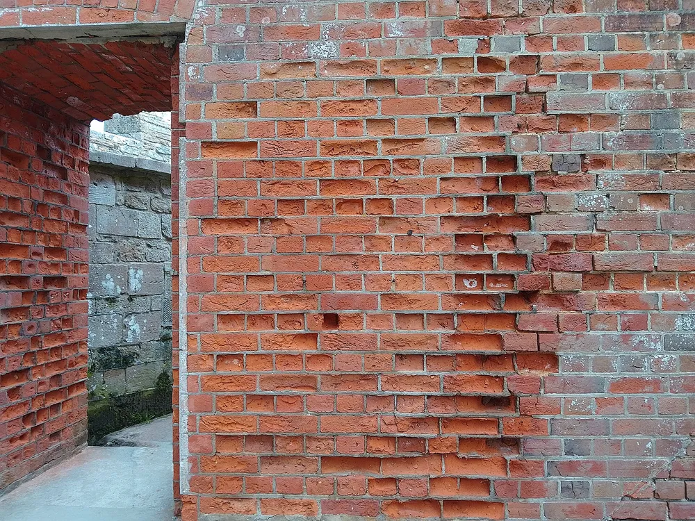 Weathered red brickwork with eroded mortar joints and spalled brick faces